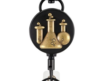 May include: A black retractable badge reel with a gold-colored science flask design. The reel has a black carabiner clip and a clear plastic badge holder with a metal ring.