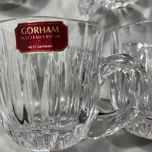 May include: Set of four clear glass teacups with a cut glass design. The cups have a label that reads "Gorham Full Lead Crystal West Germany".