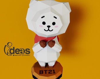May include: A white, geometric-shaped RJ character figure from BT21, wearing a red scarf and holding its hands together. The figure stands on a brown base with the text "BT21" and "RJ". The background is a solid yellow.