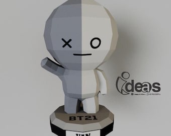 Peut inclure: Une figurine en papier blanc et gris d'un personnage de dessin animé avec un X et un O pour les yeux. Le personnage est debout sur un socle avec le texte "BT21" et "VAN" dessus.