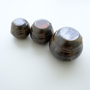 以下が含まれることがあります： 蓋付きの茶色の陶器の壺が3つ、小さい順に並んでいます