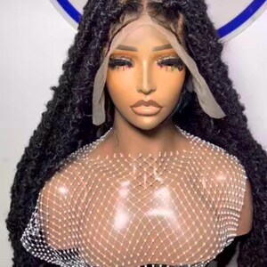 May include: A black synthetic wig with long, loose, braided dreadlocks. The wig is styled on a mannequin head with a lace front and a clear, plastic wig cap.