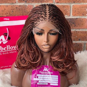 May include: A brown and black braided wig with a lace front. The wig is styled in a long, wavy bob. The wig is on a mannequin head.