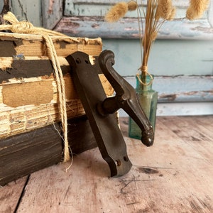May include: A vintage bronze door handle with a decorative, ornate design. The handle has a keyhole and a lever.