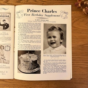 May include: A black and white photograph of Prince Charles, the future King of England, on his first birthday. He is smiling and wearing a white shirt. The photo is from a magazine article about his first birthday.
