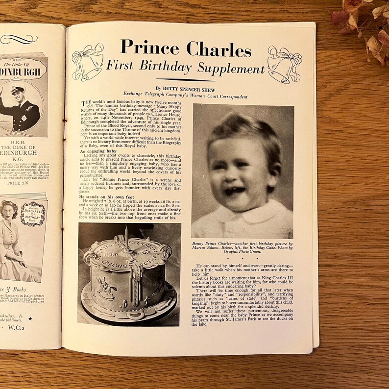 May include: A black and white photograph of Prince Charles, the future King of England, on his first birthday. He is smiling and wearing a white shirt. The photo is from a magazine article about his first birthday.