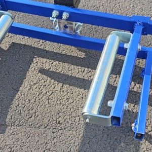 Puede incluir: Un marco de metal azul con dos rodillos plateados. El marco est&aacute; dise&ntilde;ado para soportar y mover objetos pesados.