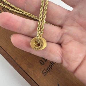 Peut inclure: Un collier en cha&icirc;ne de corde dor&eacute;e avec un pendentif rond grav&eacute; du chiffre romain 'XXXI'.