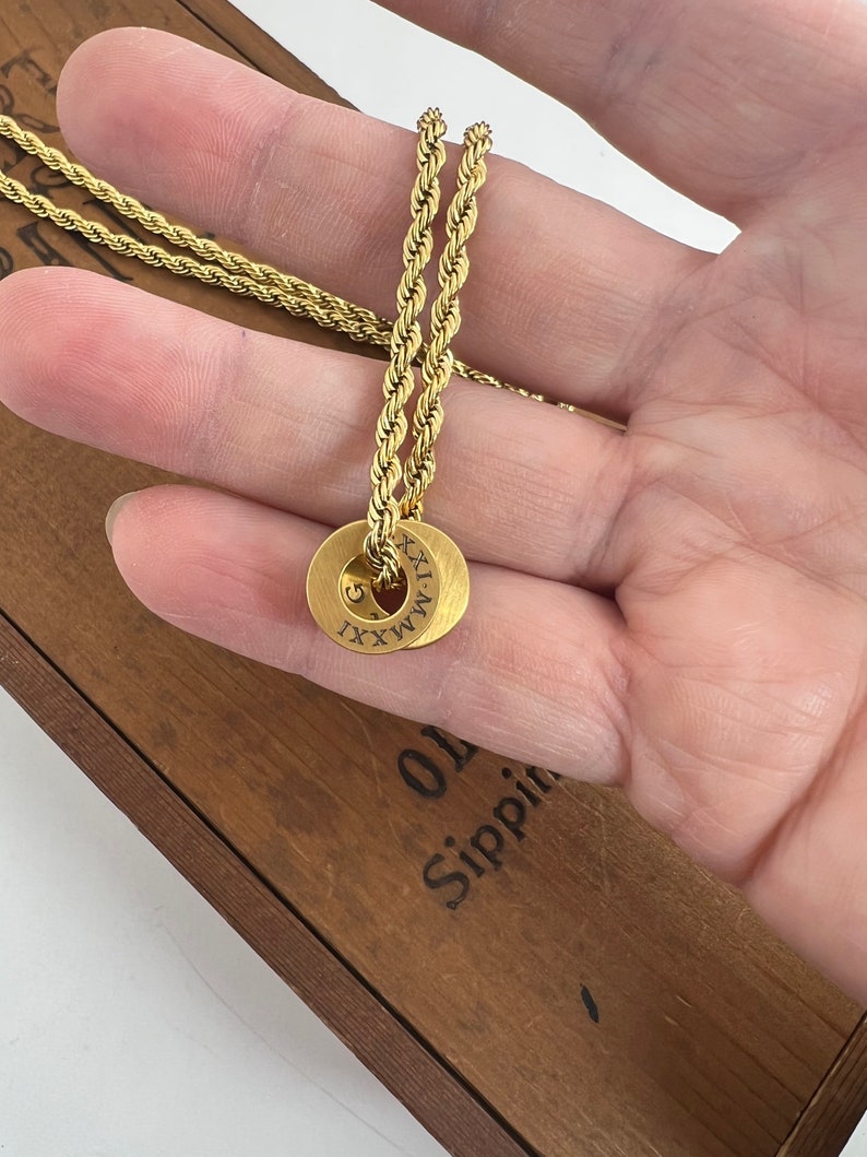 Peut inclure: Un collier en cha&icirc;ne de corde dor&eacute;e avec un pendentif rond grav&eacute; du chiffre romain 'XXXI'.