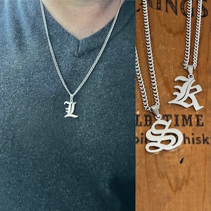 May include: Two silver chains with pendants featuring the letters 'L' and 'S' in an old English font. The chains are on a wooden background with the text 'Old Time Whiskey'.