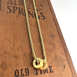 Peut inclure: Un collier en cha&icirc;ne de corde dor&eacute;e avec deux anneaux dor&eacute;s. Les anneaux sont grav&eacute;s des chiffres romains "I.XXI." et "M.XXI." et de la lettre "G". Le collier est pr&eacute;sent&eacute; sur une bo&icirc;te en bois avec le texte "ALBERTA SPRINGS OLD TIME Sipping Whisky".