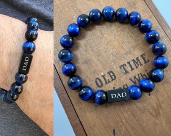 May include: Two blue and black beaded bracelets with a silver charm that says "DAD".