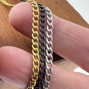May include: Three gold, silver, and black curb chains of different lengths.