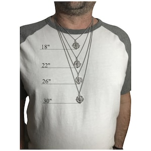 Peut inclure: Un collier avec un pendentif en forme de boussole argent&eacute; sur une cha&icirc;ne, pr&eacute;sent&eacute; sur un mannequin portant une chemise gris et blanche. Le collier est pr&eacute;sent&eacute; en quatre longueurs diff&eacute;rentes&nbsp;: 46&nbsp;cm, 56&nbsp;cm, 66&nbsp;cm et 76&nbsp;cm.