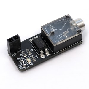 May include: A black circuit board with a clear plastic enclosure, a black chip labelled "M 0 L18 K1Z7", and a 3.5mm audio jack. The board has several components, including resistors labelled "R1", "R2", and "R3", and a connector labelled "GND".