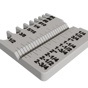 May include: A gray plastic tool with a ruler on one side and a series of drill bit size gauges on the other side. The ruler is marked in inches and fractions of an inch, from 1/2 inch to 2-3/4 inches. The drill bit gauges are marked with sizes from 1/16 inch to 1/4 inch, and with drill bit sizes #8, #10, and #14.