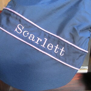May include: A navy blue saddle pad with a pink trim and the name "Scarlett" embroidered in white.