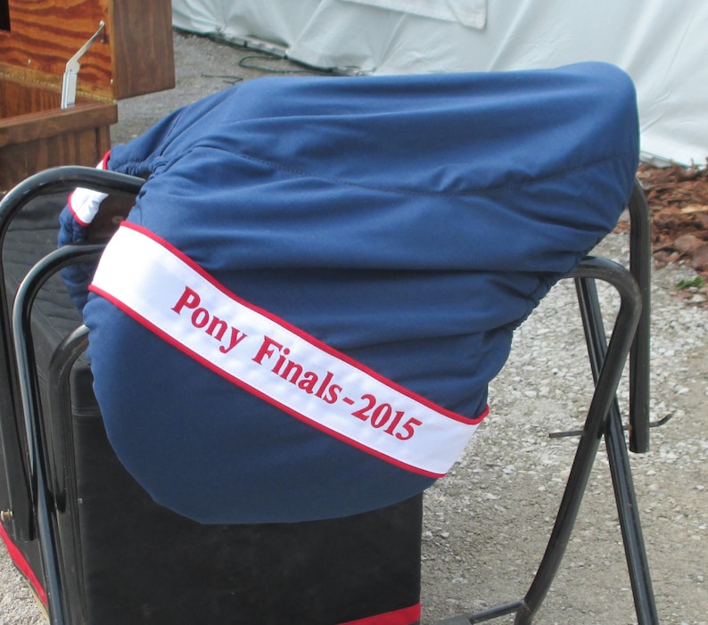May include: A blue saddle cover with a white and red ribbon that says "Pony Finals-2015".