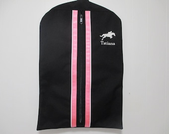 May include: Black garment bag with pink and white stripes down the centre. The bag has a zipper closure and the name "Tatiana" embroidered on the front.