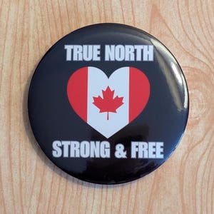 May include: A black button with a white heart featuring the Canadian flag and the text "TRUE NORTH STRONG & FREE".