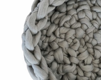 May include: A large, grey, crocheted basket made from thick yarn. The basket is woven in a circular pattern with a braided edge.