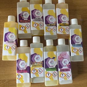 May include: Ten small yellow bottles with white labels and black text. The bottles contain different scents, including "Leonora Tropical Sunse", "Dreams Stoppable", "Dark Opium", "Lady Millionaire", "Madam", "A Day at the Fair", "Happiness is Bliss", "Alien Invasion", "Bomb Shell", and "Blue Leonora".
