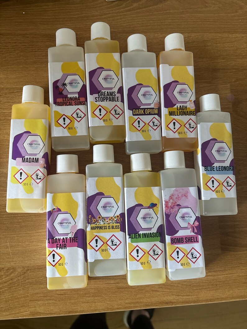 May include: Ten small yellow bottles with white labels and black text. The bottles contain different scents, including "Leonora Tropical Sunse", "Dreams Stoppable", "Dark Opium", "Lady Millionaire", "Madam", "A Day at the Fair", "Happiness is Bliss", "Alien Invasion", "Bomb Shell", and "Blue Leonora".