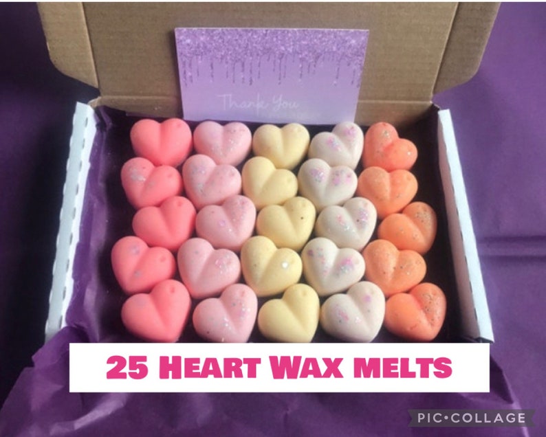 May include: A box filled with 25 heart-shaped wax melts in shades of pink, yellow, and orange. The melts are arranged in rows and have a glittery finish. The box is labeled "25 Heart Wax Melts".