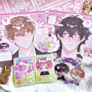 May include: Two rectangular art prints featuring anime-style characters with brown and black hair, surrounded by smaller chibi illustrations, text bubbles with question marks, and exclamation points. Two acrylic charms and two small cards are included.