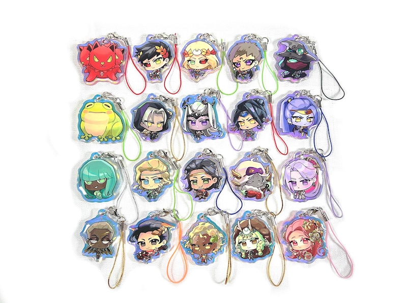 May include: A collection of 18 colorful character charms with attached strings. The charms feature various cartoon characters with different expressions and poses. The charms are made of clear acrylic and have a glossy finish.