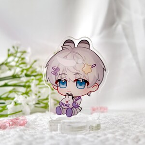 May include: A white and purple anime character with white hair and blue eyes holding a white bunny plush. The character is standing on a clear acrylic stand.