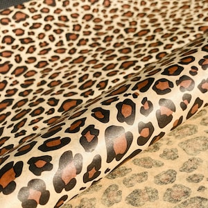 May include: Brown and black leopard print wrapping paper. The paper has a shiny, metallic finish.