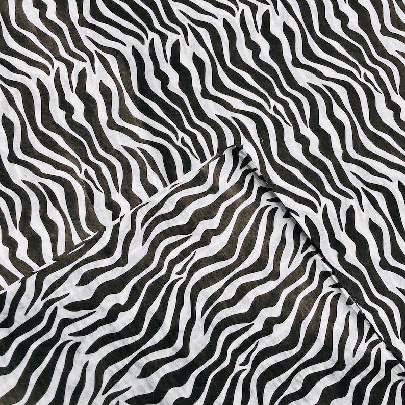 Puede incluir: Tela de estampado de cebra en blanco y negro con una superficie texturizada.