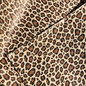 May include: A sheet of brown wrapping paper with a leopard print pattern. The paper is folded in half, and the pattern is visible on both sides.