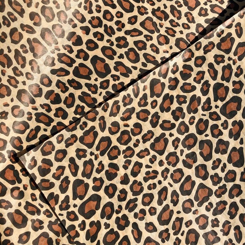 May include: A sheet of brown wrapping paper with a leopard print pattern. The paper is folded in half, and the pattern is visible on both sides.