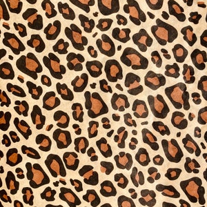 May include: A seamless pattern of brown and black leopard spots on a beige background.