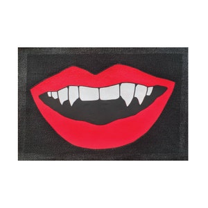May include: A red, open mouth with sharp white fangs on a black background. The mouth is painted in a cartoon style.