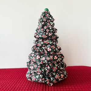 May include: A green and red Christmas tree made of fabric with a candy cane pattern. The tree is decorated with a green star on top.
