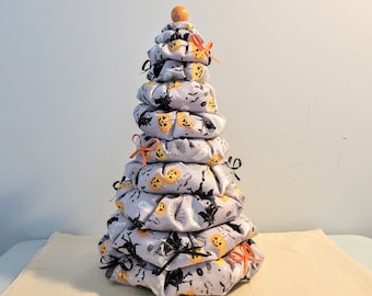May include: A tiered Halloween tree decoration made of fabric with a grey and white background and orange and black accents. The tree is decorated with pumpkins, bats, and the word "Boo".