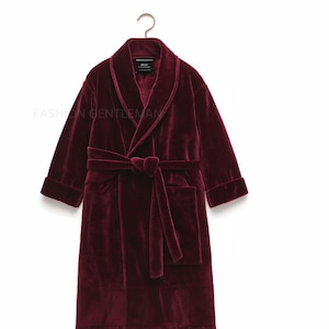 May include: A deep burgundy velour robe with a shawl collar, a self-tie belt, and a patch pocket. The robe has a black label with the word "MUJI" on it.