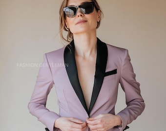 May include: A woman wearing a lavender blazer with a black satin lapel. She is wearing black sunglasses and has her hair pulled back.