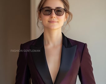 May include: A woman wearing a dark purple blazer with a black satin lapel. She is wearing sunglasses and has her hair pulled back.