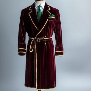 May include: A long, burgundy velvet robe with gold trim and a matching belt. The robe has a shawl collar and is lined with a white fabric.