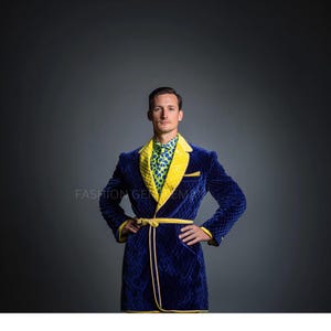 May include: A blue velvet robe with a yellow satin trim and a yellow sash. The robe has a quilted pattern and a green and white patterned shirt is visible underneath.