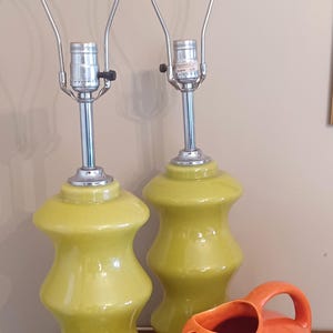 May include: Two green ceramic table lamps with chrome bases and a matching orange ceramic jug.