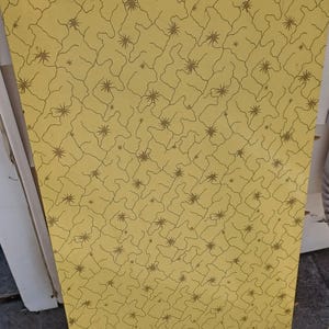 May include: A rectangular panel with a yellow background and a repeating pattern of brown lines and star-like shapes. The design has a vintage or retro aesthetic.
