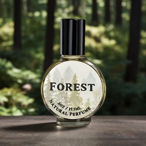 May include: A clear glass bottle of natural perfume with a black cap and a white label that says "FOREST .6oz / 17.5ML NATURAL PERFUME". The label has a blurry image of a forest in the background.