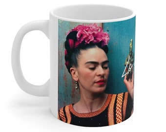 May include: White ceramic mug with a colorful image of Frida Kahlo holding a cactus. The image is against a blue background. The text "Love" is written in white on the cactus.