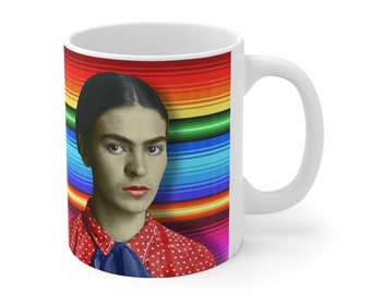 May include: White ceramic mug with a colorful striped background and a portrait of Frida Kahlo in a red polka dot shirt.