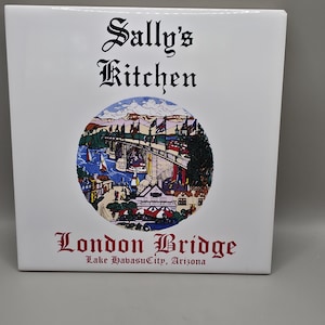 May include: A square white ceramic tile featuring the black text Sally's Kitchen at the top. A circular illustration depicts the London Bridge in Lake Havasu City, Arizona, with boats and buildings. The text London Bridge and Lake Havasu City, Arizona appears below.